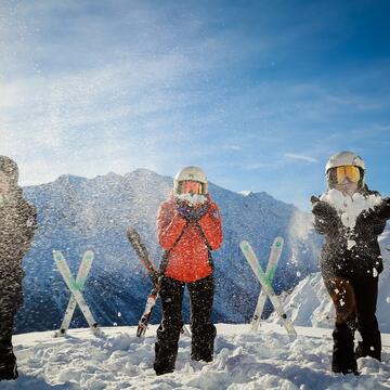 Trois skieur qui souffle sur la neige qu'ils ont dans les mains
